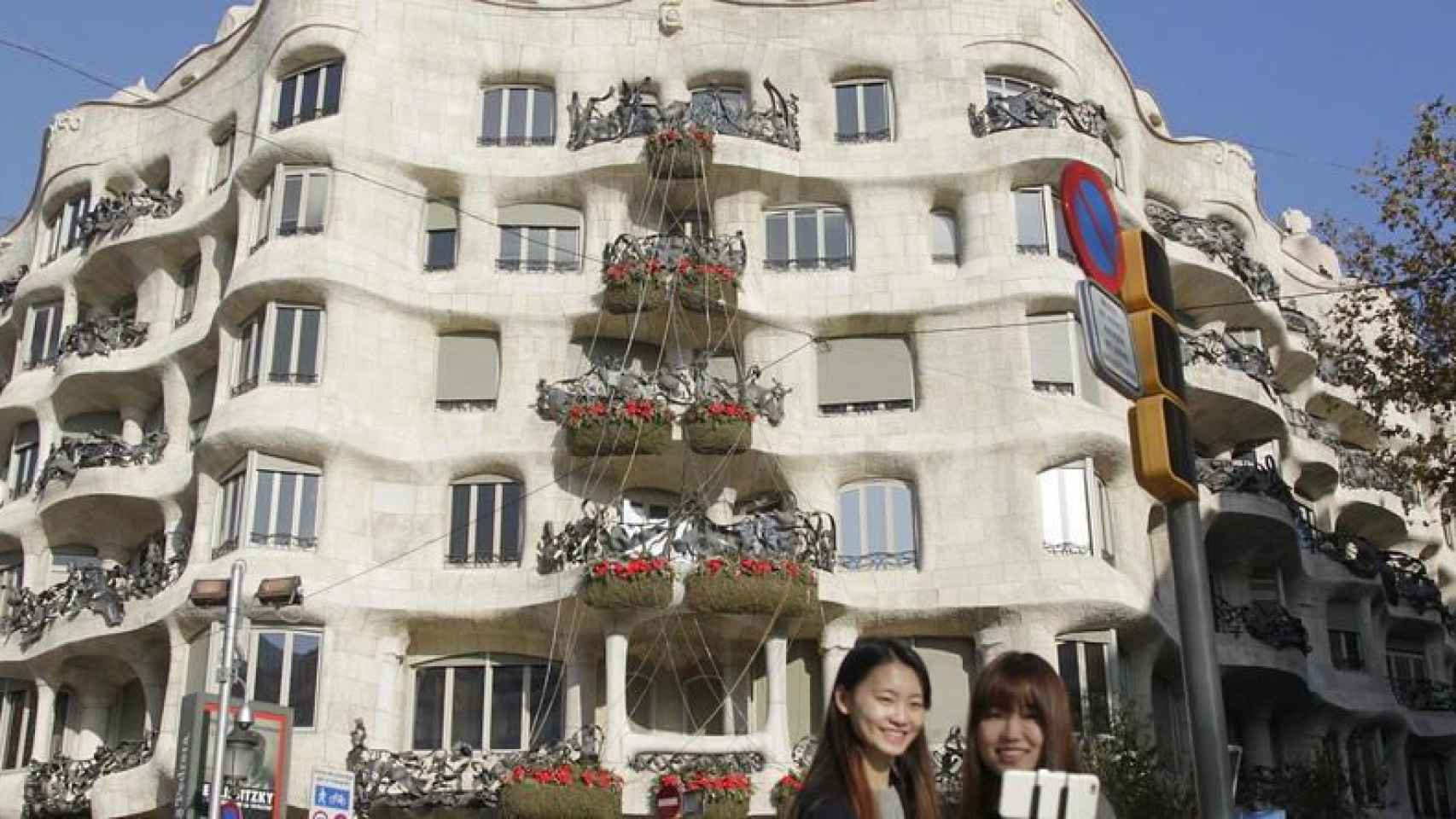 Dos turistas se toman una foto frente a La Pedrera / EFE