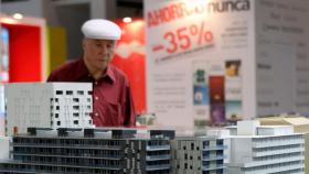Imagen de un posible comprador de vivienda mirando la maqueta de una promoción en oferta, que se vende mediante hipotecas / EFE