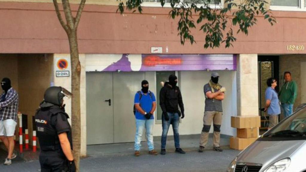 Agentes de la Policía Nacional vestidos de paisano y encapuchados en la puerta del almacén de la sede nacional de la CUP en el marco de la macrooperación de la que ha informado el TSJC / CG