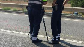 Los agentes de los Mossos d'Esquadra estudian el lugar donde un joven atropelló de muerte a dos ciclistas en Montbrió
