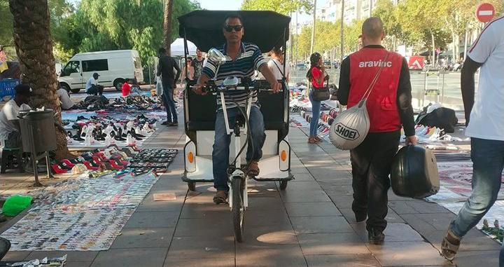 Un 'trixie' por la acera de la avenida Juan de Borbón de la Barceloneta junto a una fila de manteros en septiembre / CG