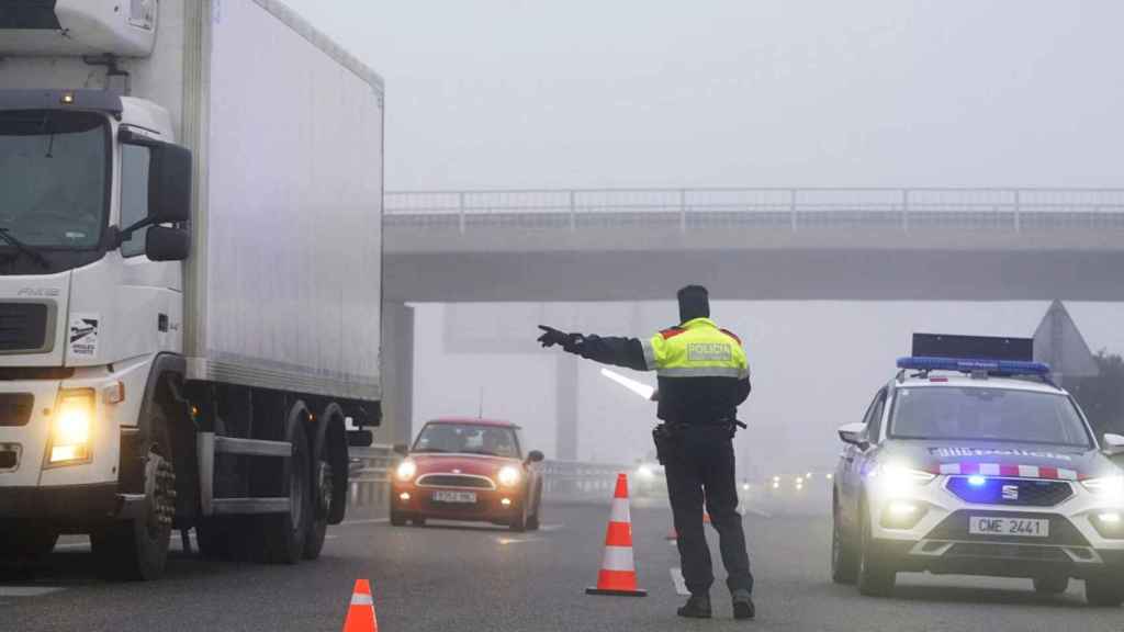 Imagen de un mosso d'esquadra dirigiendo el tráfico entre la niebla / EFE