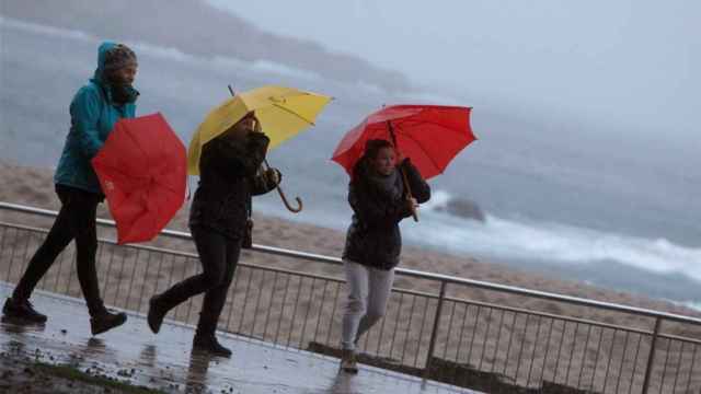 Tres chicas combaten la lluvia y el viento de un temporal / EFE