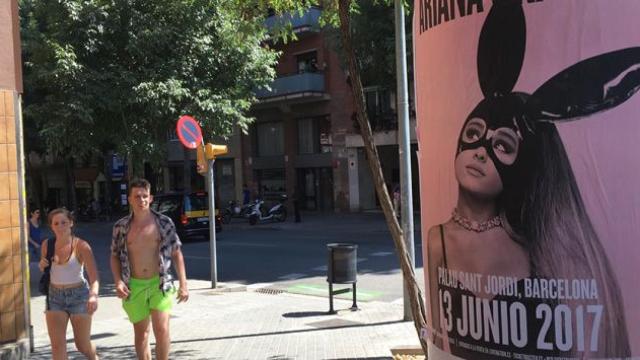 Unos turistas aprecian el cartel que anuncia el concierto de Ariana Grande en Barcelona en la calle Sardenya / CG