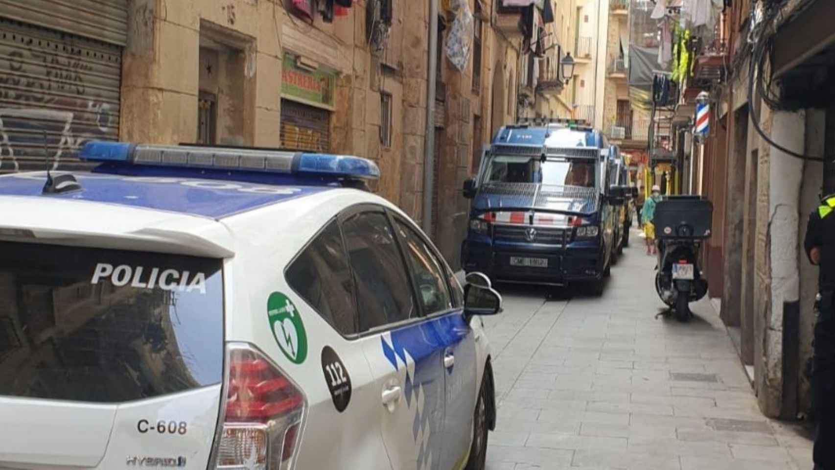 Vehículos de la Urbana y de los Mossos apostados bajo el piso en el que se ha desplegado el operativo en Ciutat Vella / MOSSOS