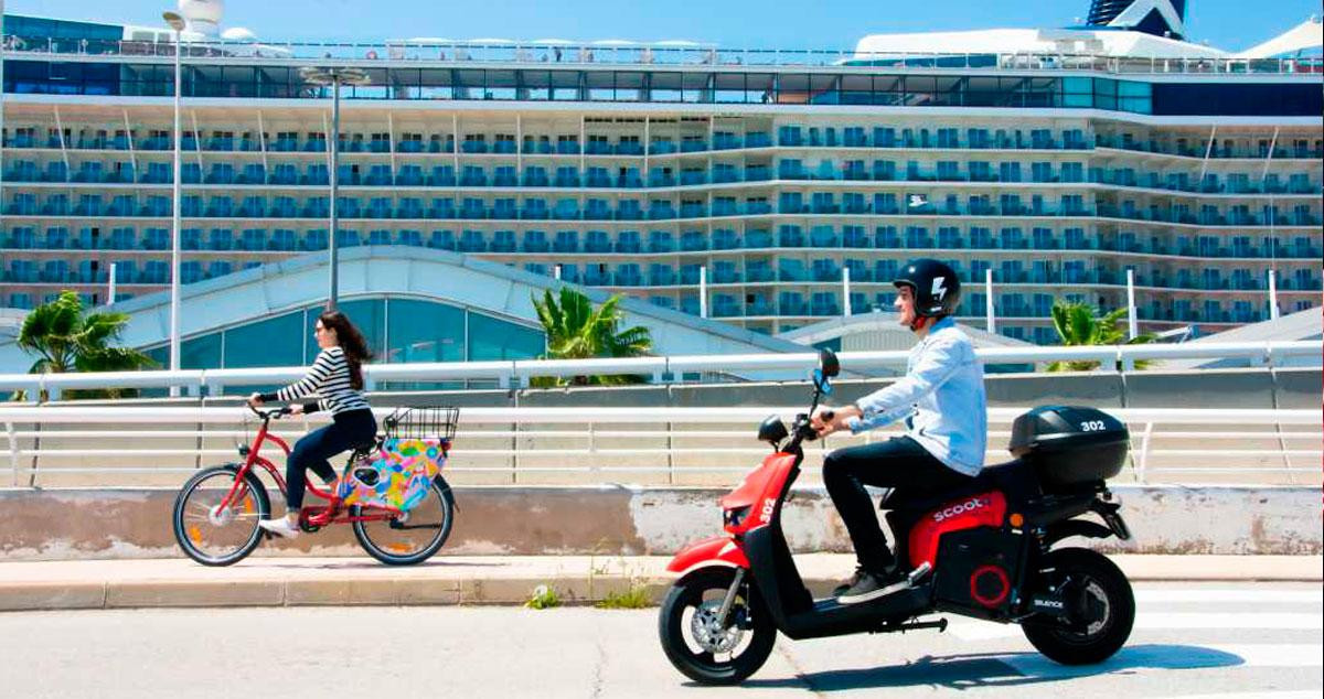 Imagen de una moto eléctrica y una bicicleta Scoot frente a un crucero en Barcelona / CG