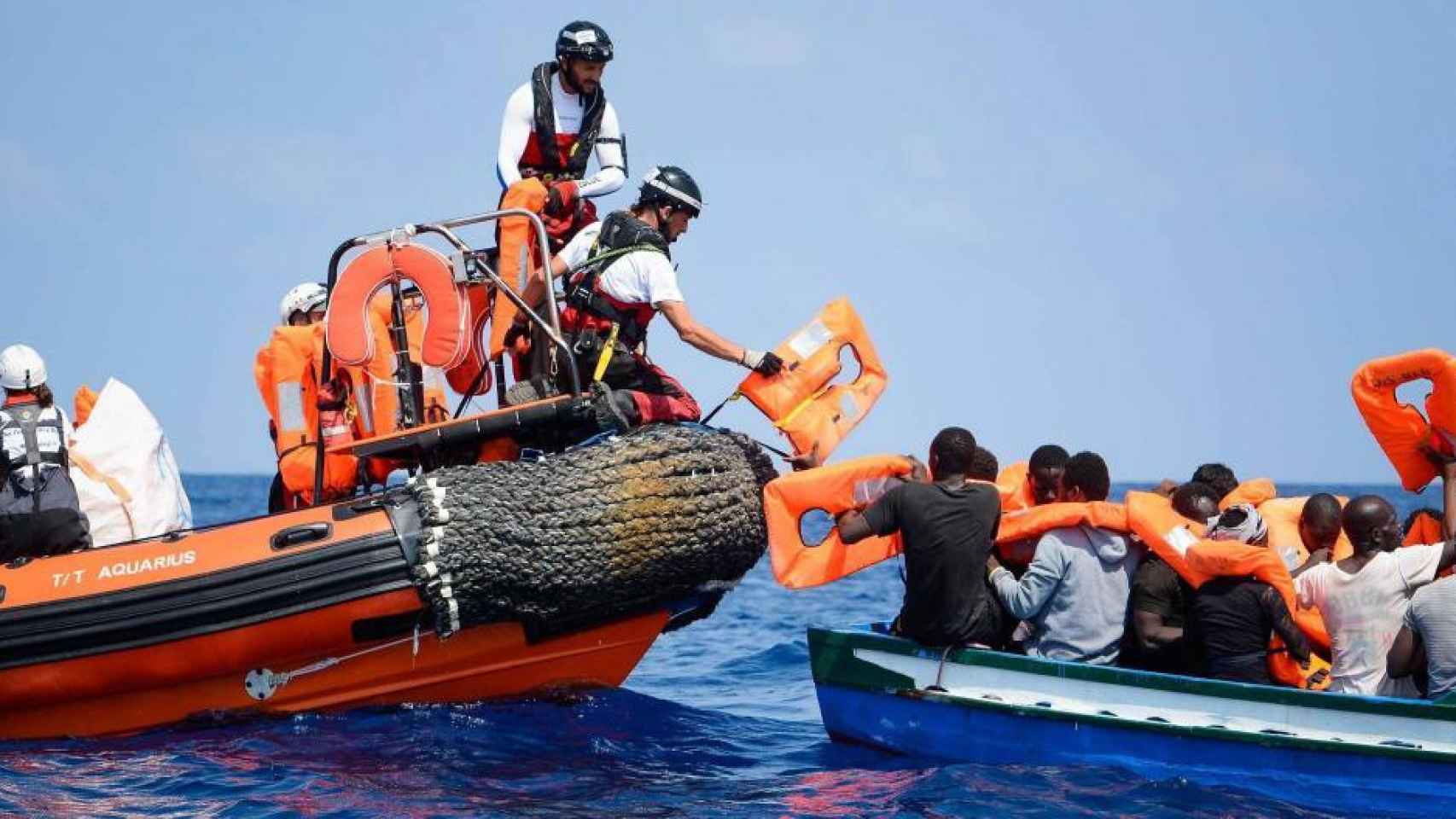 Voluntarios ayudan a un grupo de refugiados a trasladarse hacia el buque Aquarius / EFE