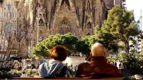 Dos turistas contemplan la Sagrada Familia de Barcelona.