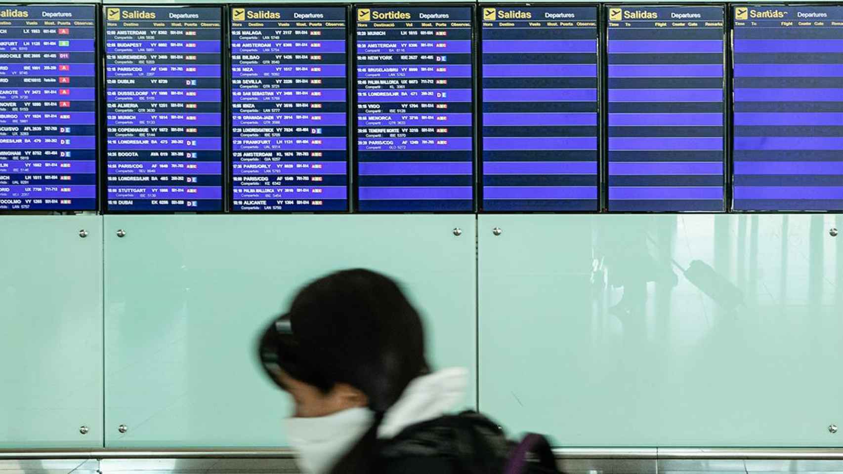 Una pasajera con mascarilla observa los paneles del aeropuerto El Prat (Barcelona) / XAVIER BONILLA - EUROPA PRESS