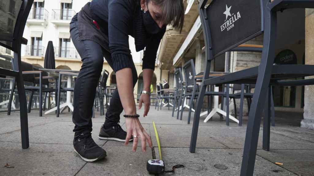 Una camarera mide la distancia de seguridad en una terraza por la tercera ola de Covid / EP