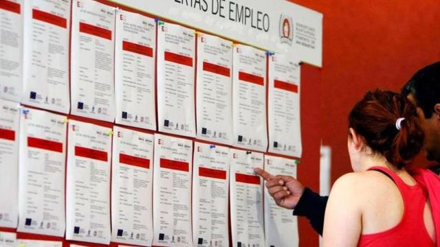 Dos personas en paro buscan un empleo en un tablón de anuncios / EFE