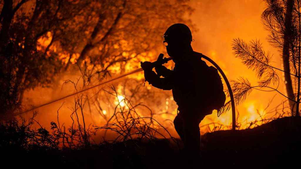 Un bombero participa anoche en la extinción de un incendio próximo al núcleo do Pereiro, en el municipio de Castrelo de Miño (Ourense), del que ha tenido que ser desalojado algún vecino por precaución ante la cercanía del fuego / EFE - BRAIS LORENZO