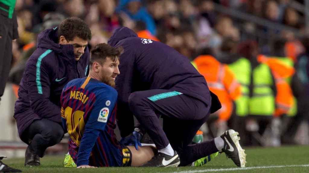 Messi es atendido en la banda durante el Barça-Valencia / EFE