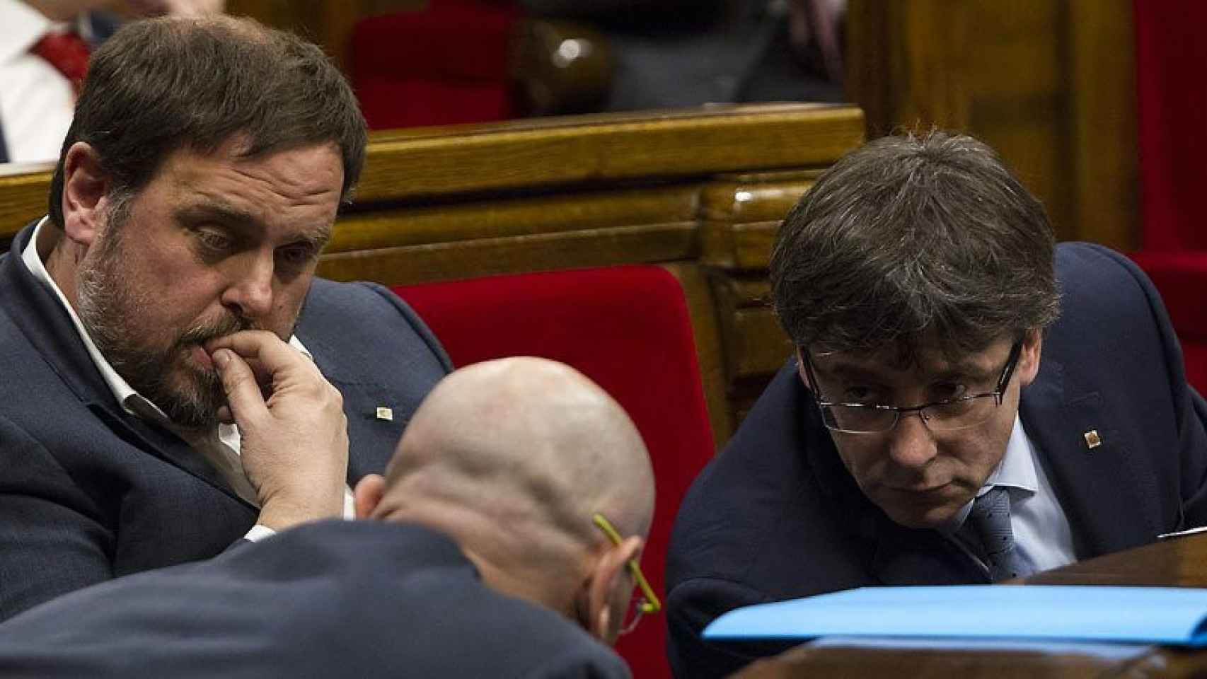 Oriol Junqueras (izquierda), Carles Puigdemont (derecha) y Raül Romeva (de espaldas) en una imagen de archivo en el Parlament.