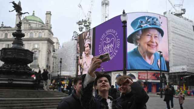 Unos jóvenes posan frente a una foto de la reina Isabel II por su Jubileo de Platino en Piccadilly Circus / EFE