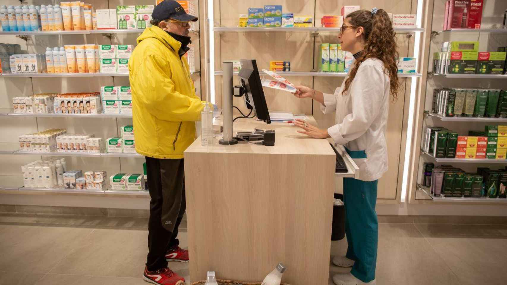 Una trabajadora atiende a un hombre en una farmacia / EP