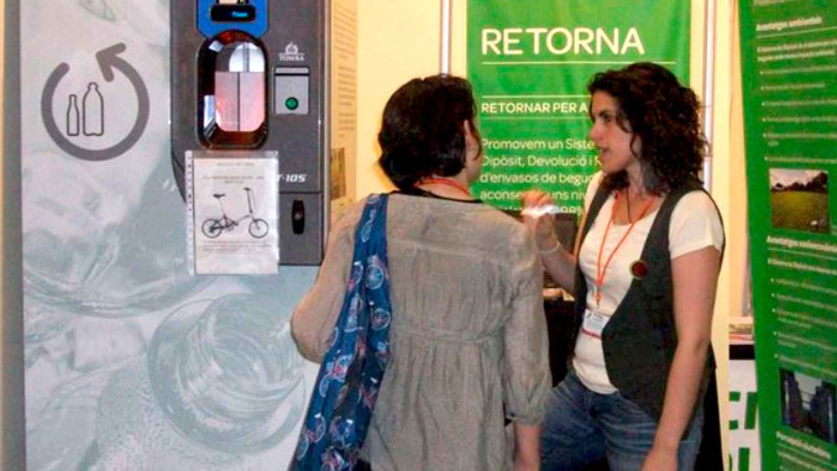 Representantes de la asociación medioambiental Retorna explican el funcionamiento del sistema SDDR. Encima del botón verde se puede ver el nombre de Tomra, el fabricante de la máquina / RETORNA