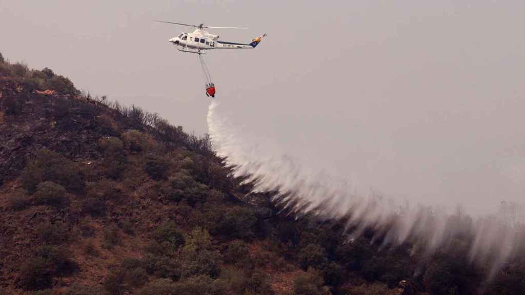 Un helicóptero en San Pedro de Trones, trabajando en las labores de extinción del incendio procedente de Galicia que afecta al municipio de Puente de Domingo Flórez, y que se ha reactivado en las últimas horas debido al ascenso de las temperaturas y al cambio del viento / EFE - ANA F. BARREDO