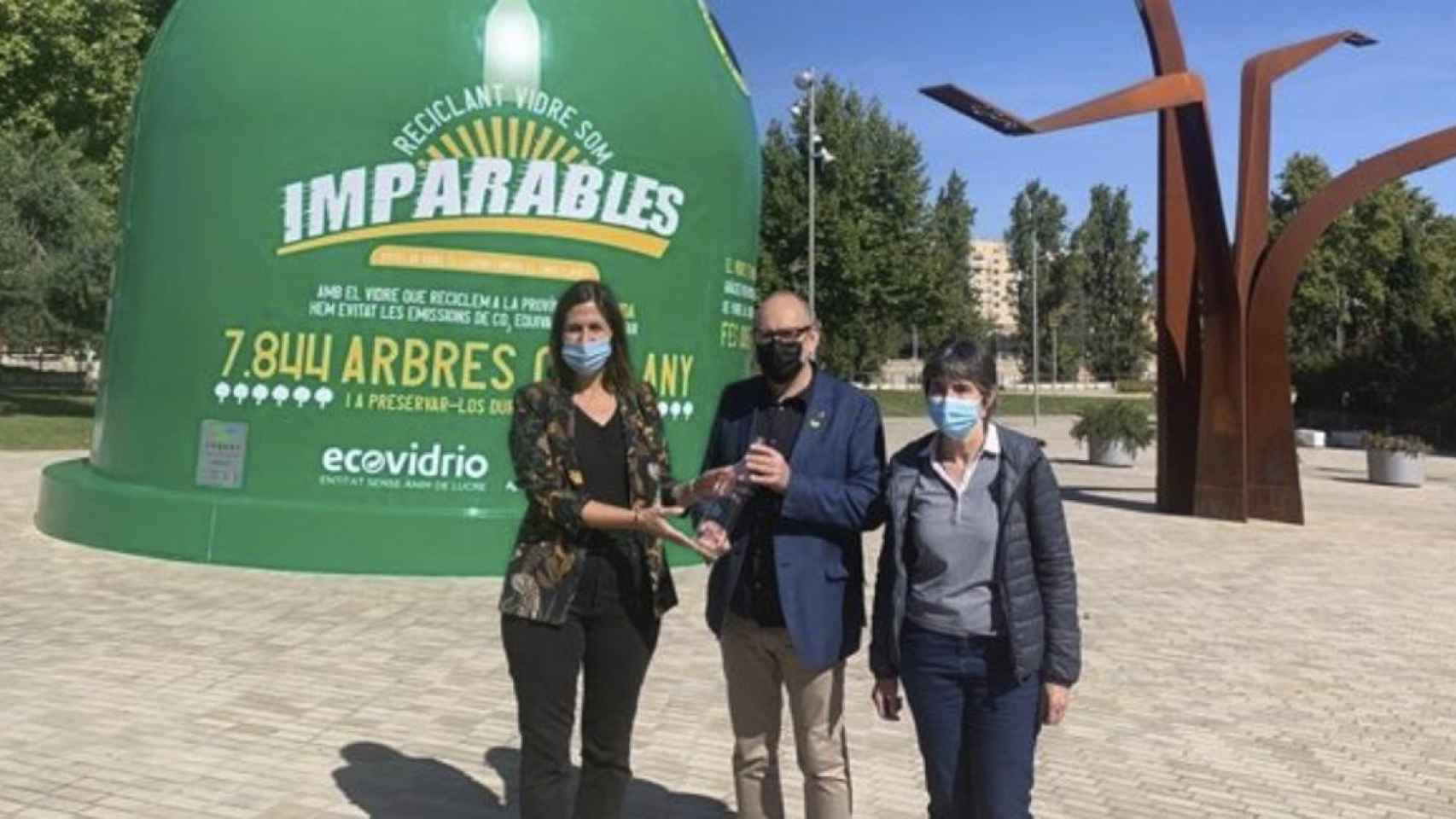 La gerente de Ecovidrio en Cataluña, Silvia Mayo, el concejal del Ayuntamiento de Lleida, Jaume Rotllant y la coordinadora de sostenibilidad, Esther Fanlo, enfrente del contenedor de vidrio más grande del mundo / EP