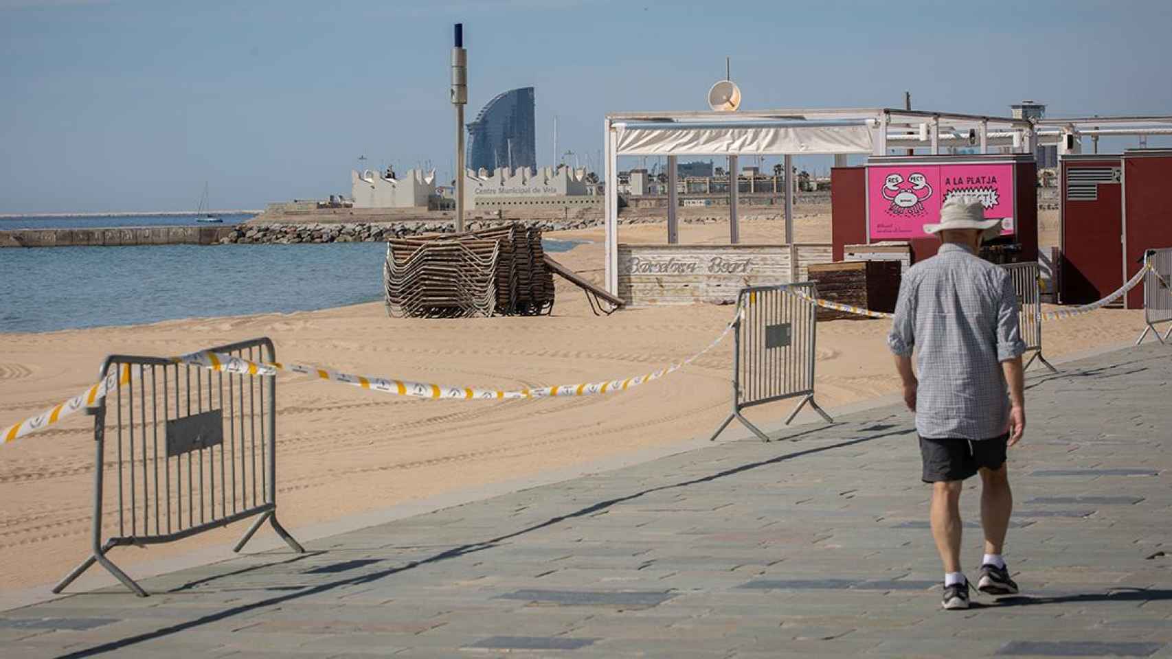 Un hombre pasa junto a la base náutica de la playa del Bogatell / EP