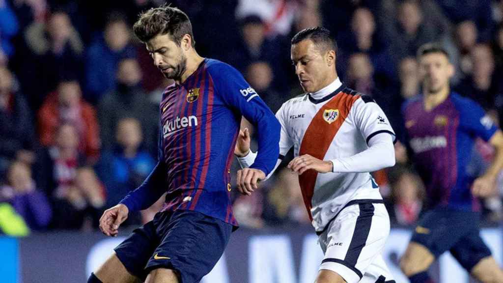 El defensa del FC Barcelona Gerard Piqué (i) juega un balón ante Raúl de Tomás, del Rayo Vallecano / EFE
