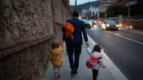 Dos niñas de la mano con un hombre a su llegada al primer día de clase, donde según los expertos se incrementa el acoso escolar / EP