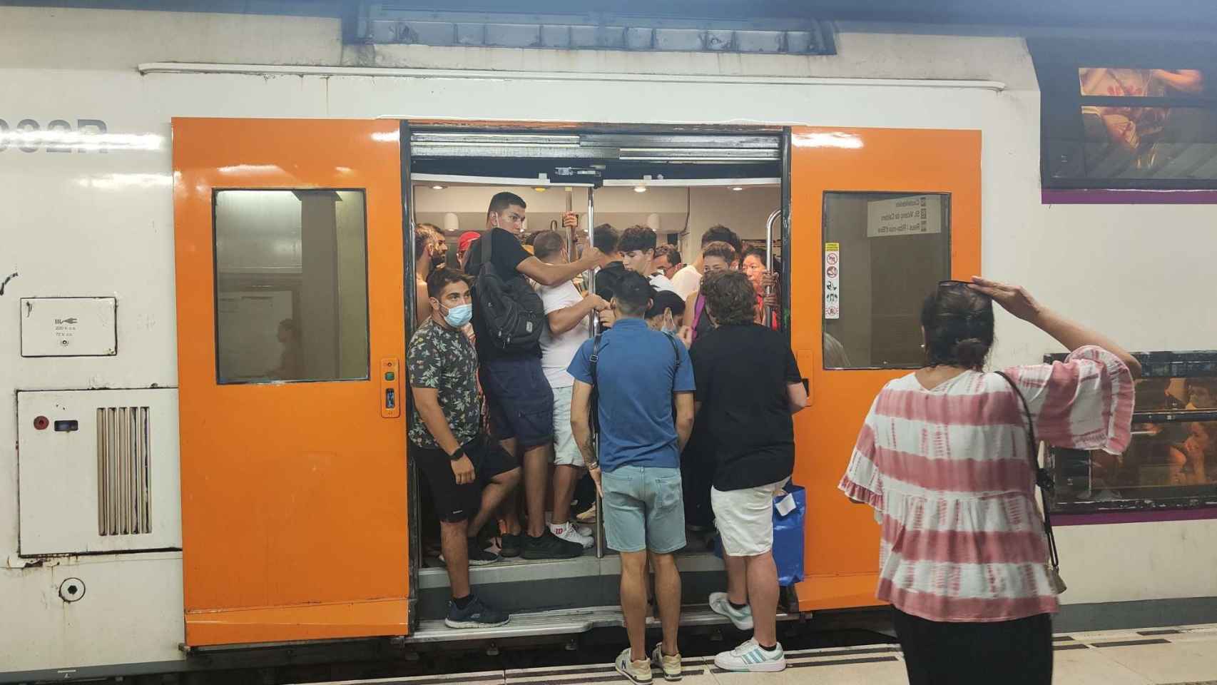 Tren de Rodalies de la R2 con el aforo completo en una de las estaciones, mientras tres personas miran cómo acceder / CG