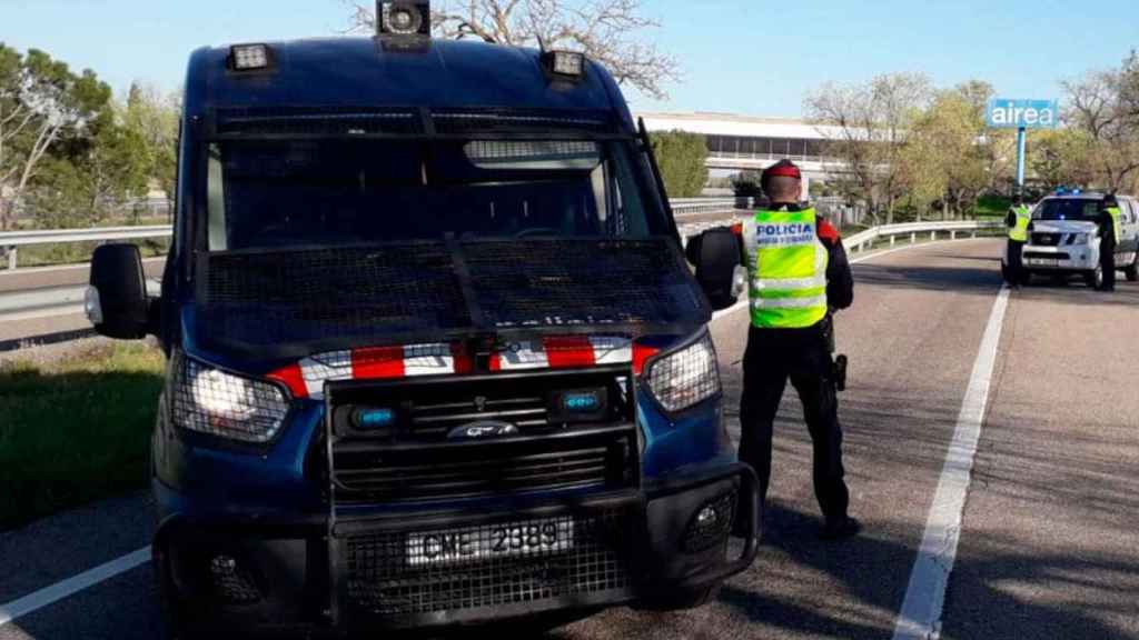 Agentes junto a un furgón de los Mossos ante una población confinada por el coronavirus / MOSSOS