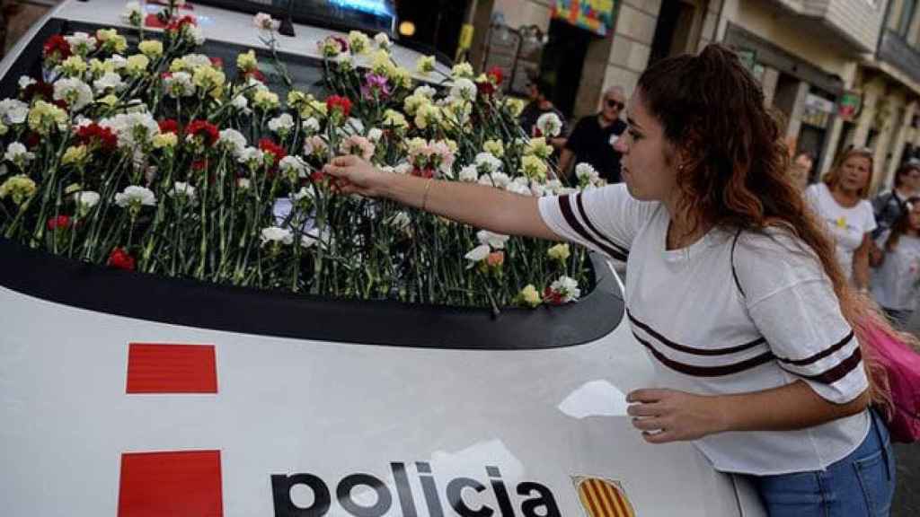 Una joven coloca un clavel en un coche de los Mossos d'Esquadra / CG