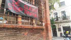 Una moto pasa frente a una pancarta contra el tanatorio de Sants en la fábrica Germans Climent / CG