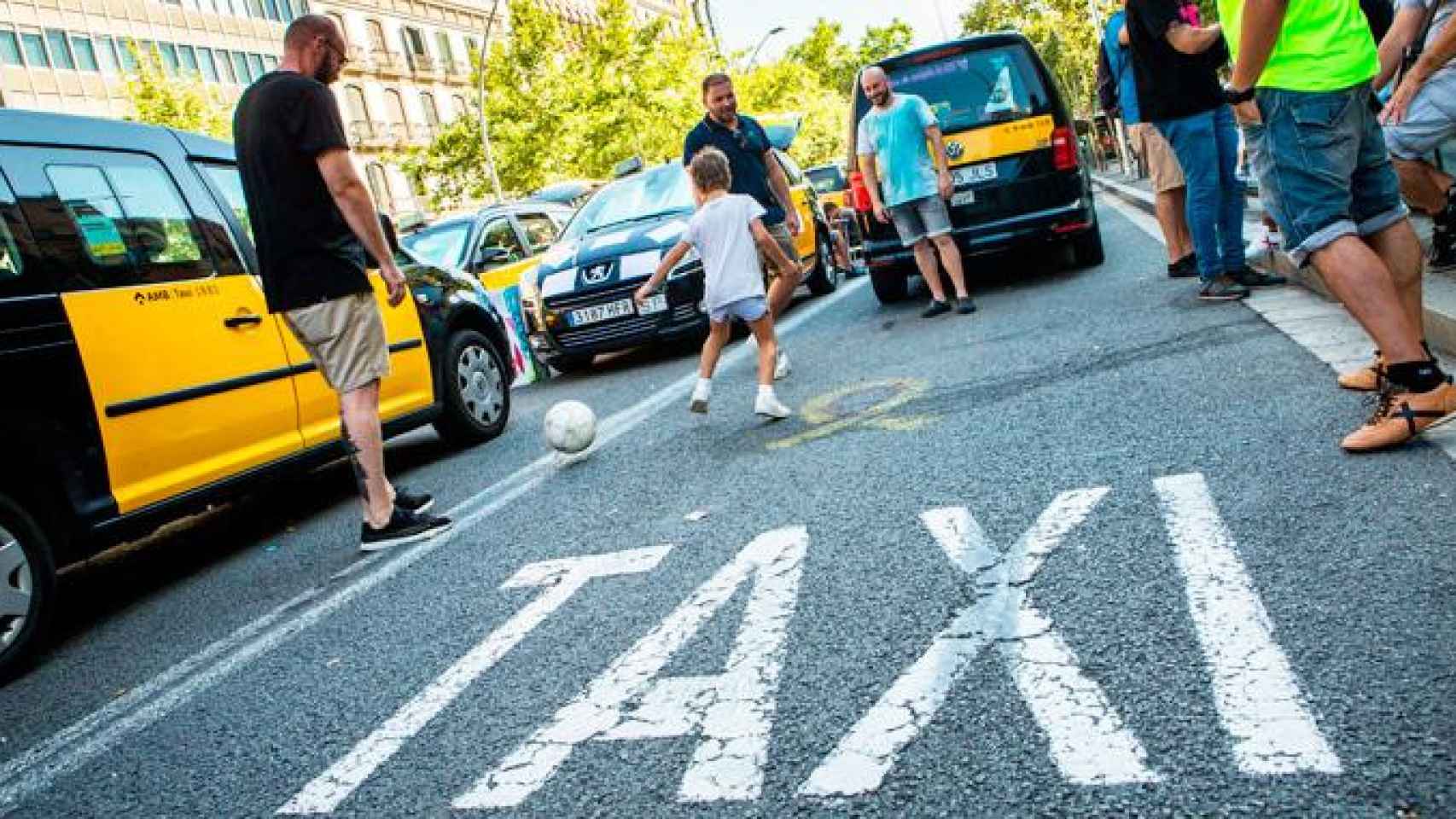 Taxistas con sus hijos jugando en la calzada del centro de Barcelona / EFE