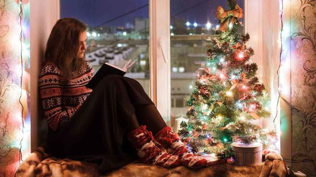 Chica con jersey navideño junto al árbol