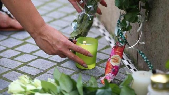 Una mujer enciende una vela en el homenaje a las víctimas mortales del atentado en Munich.