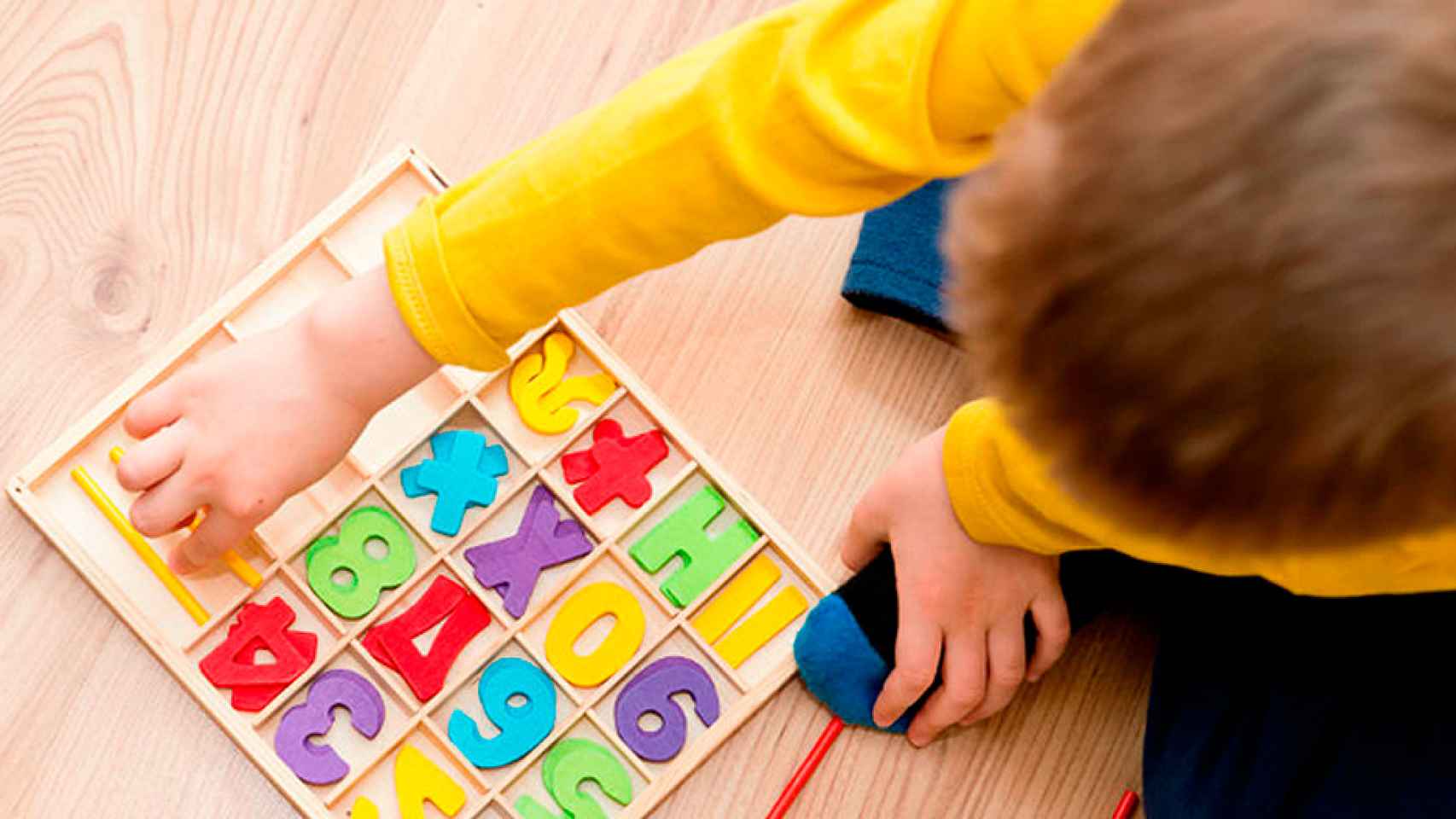 Un niño jugando en la escuela con letras y números / CG