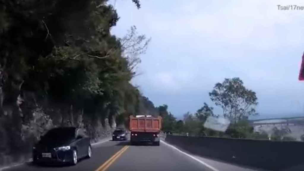 Los coches circulan momentos antes de que una roca gigante caiga encima de la calzada