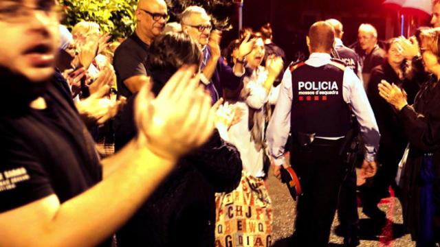 Una pareja de Mossos d'Esquadra salen entre aplausos de una escuela del barrio de Sarriá de Barcelona / EFE