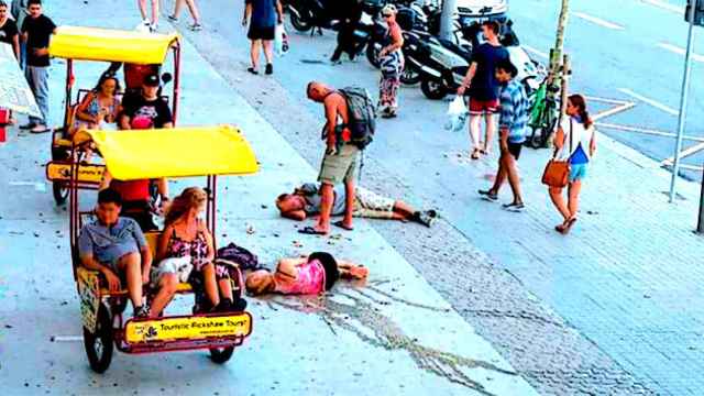 Unos turistas 'descansan' en el paseo Joan de Borbó en el barrio barcelonés de la Barceloneta / DEFENSA LA BARCELONETA