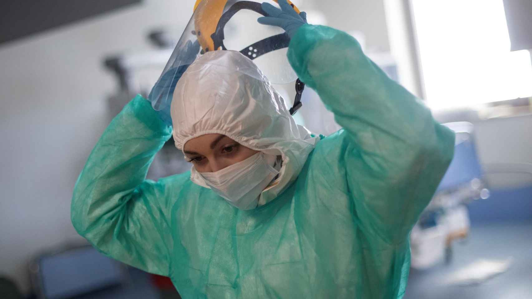 Una sanitaria se retira la pantalla protectora en la uci del Hospital Universitario Ramón y Cajal, en Madrid / EP