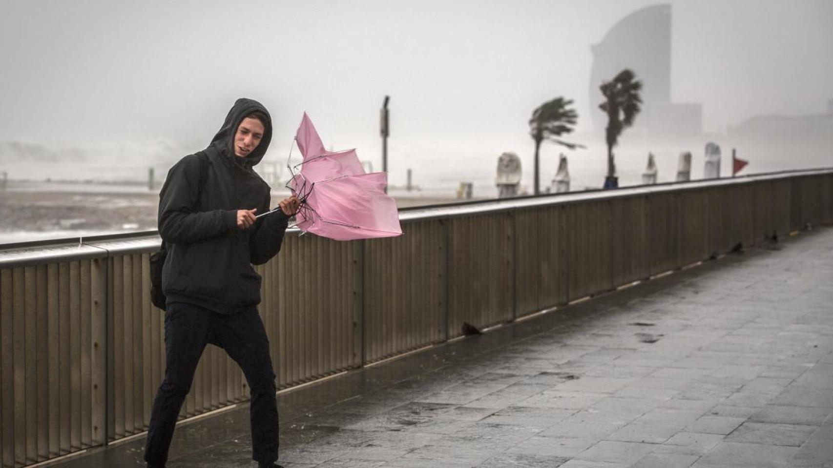 Un joven sujeta un paraguas bajo una fuerte lluvia