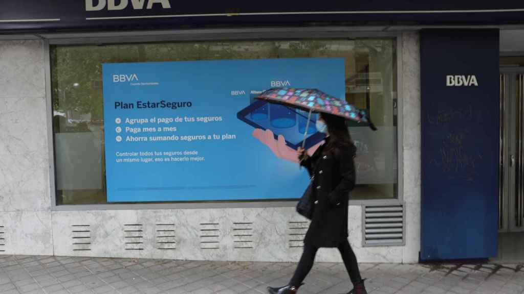 Una persona pasa por delante de la puerta de una oficina del BBVA en Madrid, en una imagen de archivo