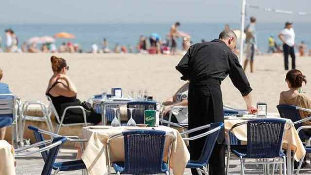 Un camarero sirve las mesas de la terraza de un restaurante en la playa / EFE
