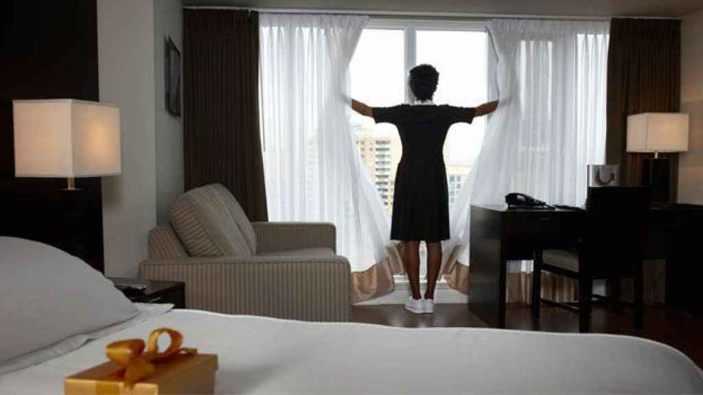 Una camarera de piso, en plena preparación de una habitación de hotel / CG