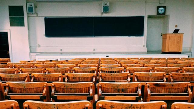 Aula vacía con pizarra, sillas y una tarima / CG