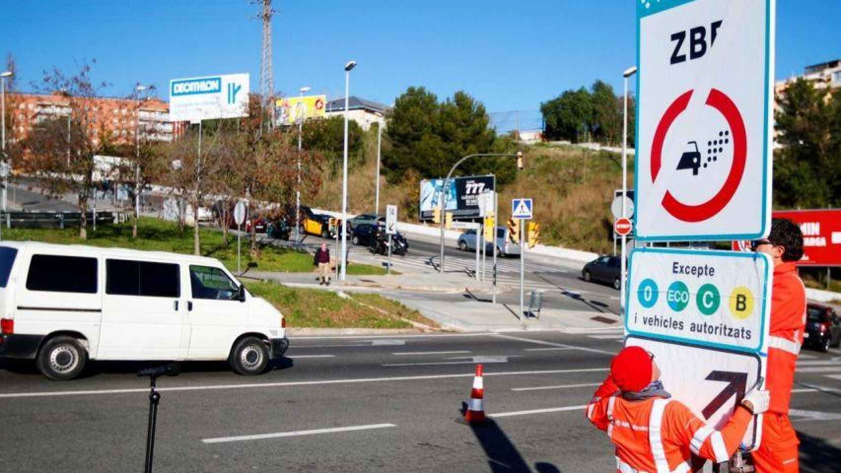 Técnicos colocan un cartel de la ZBE / EFE