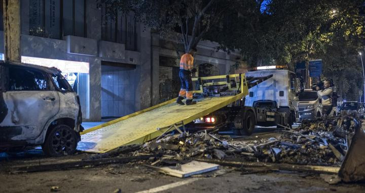 Operario retirando coches calcinados en Roger de Flor / LENA PRIETO