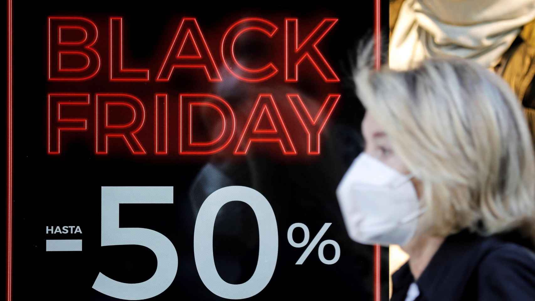 Una persona pasa ante un escaparate de un comercio con promociones del Black Friday / EFE