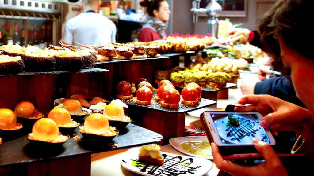 Una turista fotografía con su teléfono móvil un pintxo en un bar de la Parte Vieja de San Sebastián / EFE