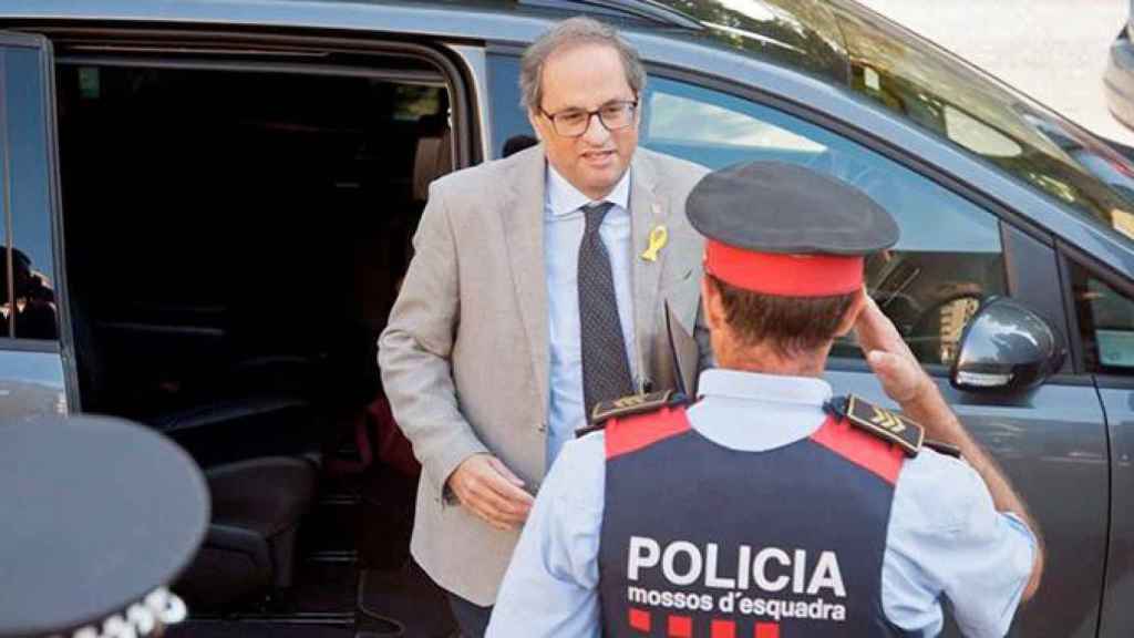 El presidente de la Generalitat, Quim Torra, saludado por un agente de los Mossos d'Esquadra. 'Hay que cuadrar a los de la escuadra', por Ramón De España / EFE