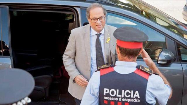 El presidente de la Generalitat, Quim Torra, saludado por un agente de los Mossos d'Esquadra. 'Hay que cuadrar a los de la escuadra', por Ramón De España / EFE