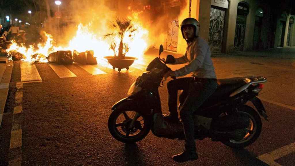 Un motorista se encuentra con una barricada de fuego en las Ramblas / EFE